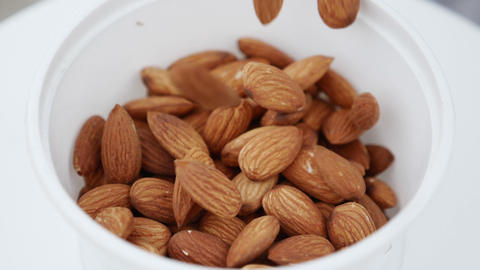 Organic Almonds falling on wooden background. Slow motion