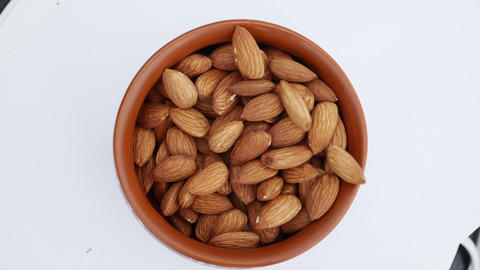 Almonds falling down into glass bowl. Slow motion. Close up.Sprinkle salt on almonds nut. product