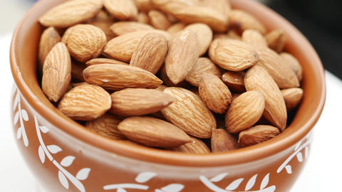 Almond on white background. Picking almonds from a bowl close up footage. Almond nut for healthy