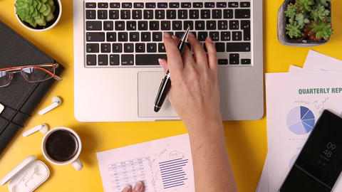 Business woman hands writing on report and typing on laptop top view