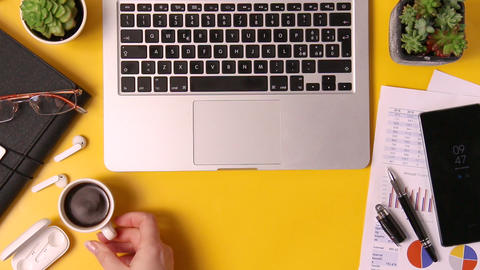 Young woman hand drinking coffee on yellow office desk