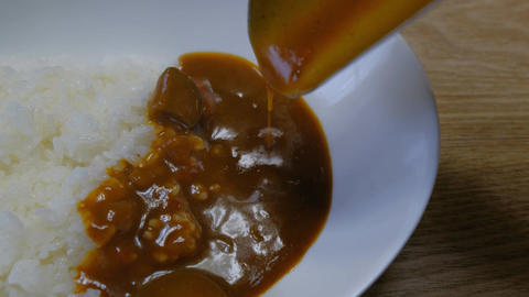 Pouring roux over curry and rice. Curry of Eggplant and Tomato