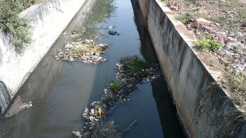 city channel with sewage and plastic packaging