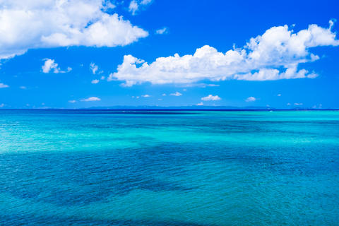 沖縄の青い海と遠くの島と真っ白な雲