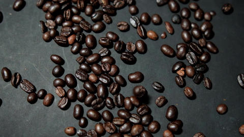 Bunch of roasted coffee beans being poured onto black surface