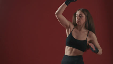Young sportswoman training, jumping, boxing, kicking, stretching, raising leg