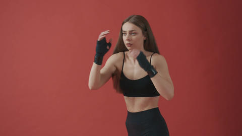 Young, slim sportswoman with long hair standing, boxing, kicking, stretching