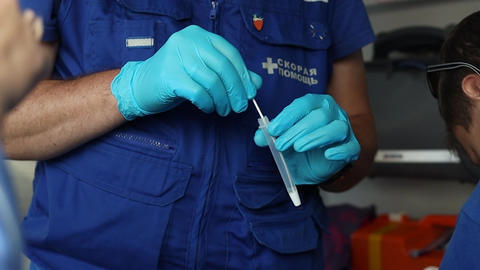 Gloved hand dips a Cotton Swab in a Transparent Tube in Clear Solution