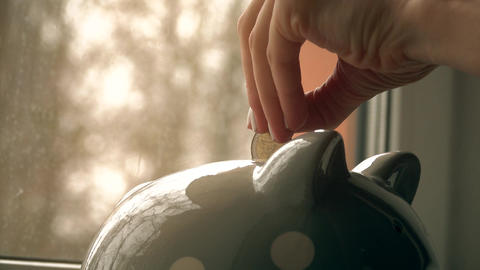 Young woman puts euro coins into piggy bank. Savings concept