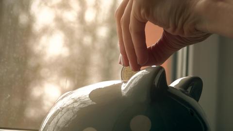 Young woman puts euro coins into piggy bank. Savings concept