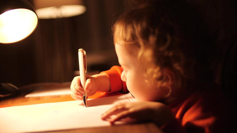 Little baby girl draws something in the evening