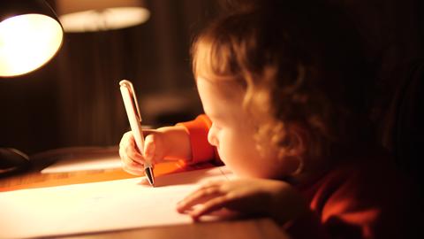 Little baby girl draws something in the evening