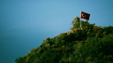 Waving flag of Turkey on the top of a green hill