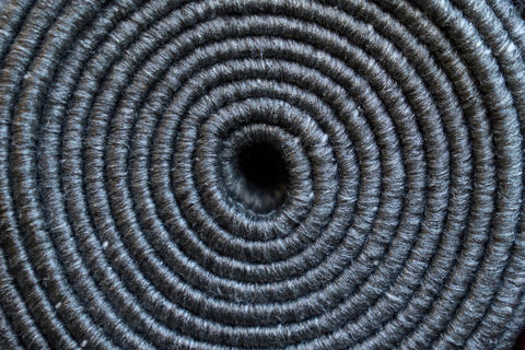 Relief texture of rolled up grey textile carpet as background