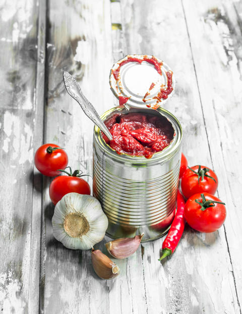 Tomato sauce in a tin can with a spoon, garlic and pepper