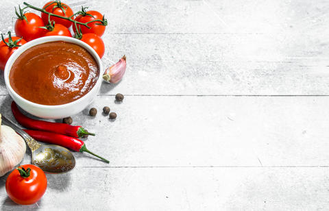 Tomato sauce in bowl with spoon, garlic and cherry