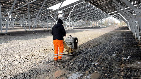 An employee using a vibrating machine compresses the rubble on the future