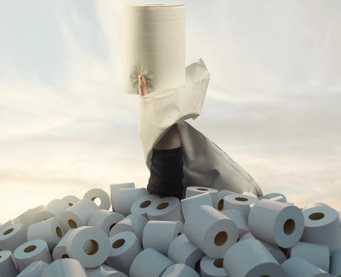 hand raising with a big toilet paper from a heap full of toilet