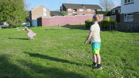 Young children, girl and boy, are playing frisbee in the open green area