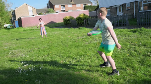 Young children, girl and boy, are playing frisbee in the open green area