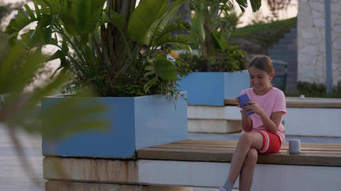 Teenage girl sits on a bench posting in social media apps, chatting with friends