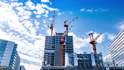 [ 4K Timelapse ] Cranes towering over a skyscraper under construction and blue sky