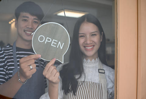 Young men and women standing smiling and holding open signs