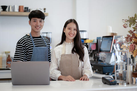 A coffee shop business owner greets customers with a smiling fac