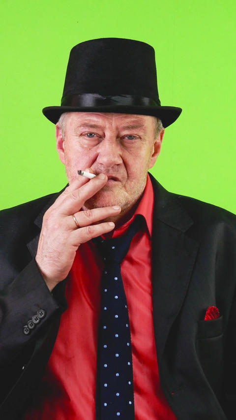 Old-fashioned brutal mature man in suit smoking cigarette, salute with his
