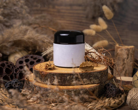 Cream jar with blank label on wood near natural decorations clos