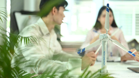 A wind turbine model on a meeting table with engineer team brainstorming project