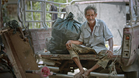 A smiling Asian man who is a poor elderly ragpicker or has a career collecting garbage