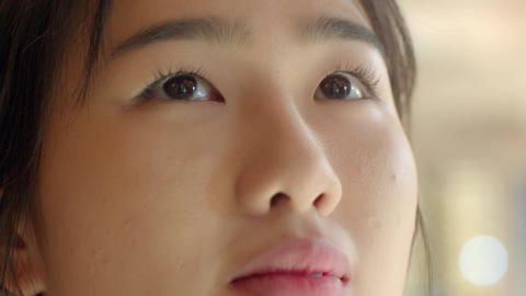 An Asian female student in a white school uniform is looking blankly upwards