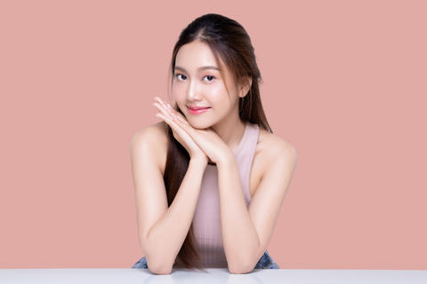 Beautiful young Asian woman with healthy and perfect skin on isolated pink background