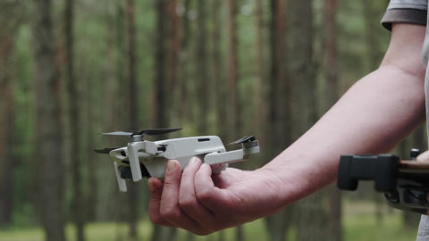 A quadcopter operator with a remote control holds the dr GIF 33439209 ...