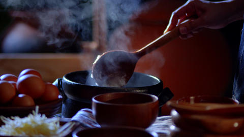 Cook uses a wooden ladle to scoop porridge into a wooden bowl in a retro style