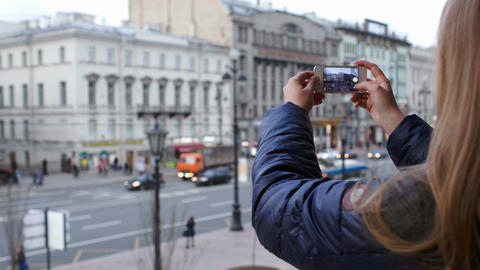 Woman with smartphone taking pictures of city with