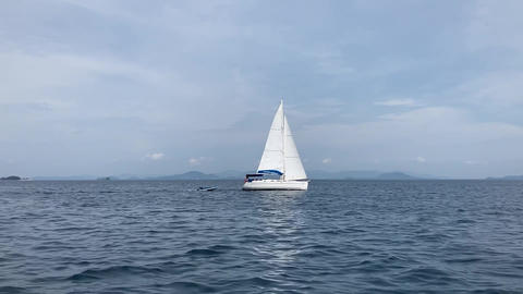 video clip of white sailboat sails in the middle of the dark blue sea