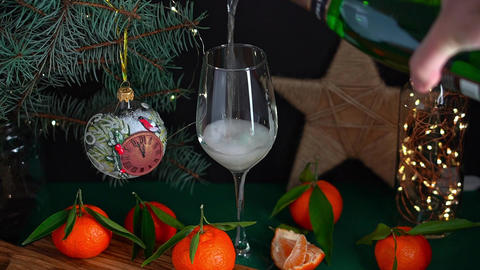 Pouring sparkling wine into wineglass on table with mandarins fir brunch and