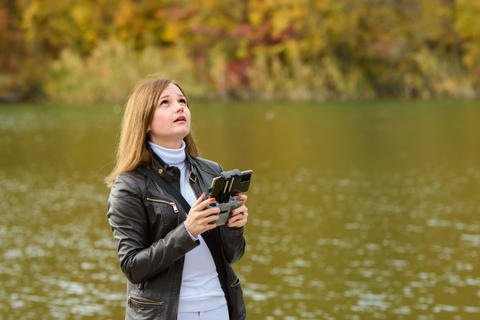A young beautiful girl launches a radio-controlled quadcopter on the shore of an