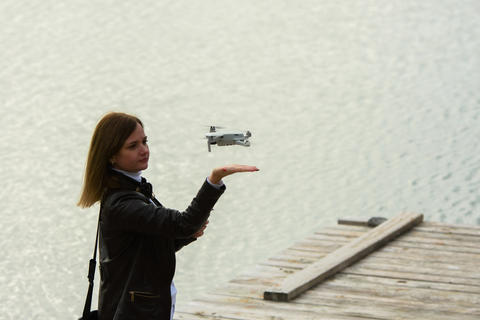 A young beautiful girl launches a radio-controlled quadcopter on the shore of a