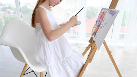 Little girl painting on easel in art studio