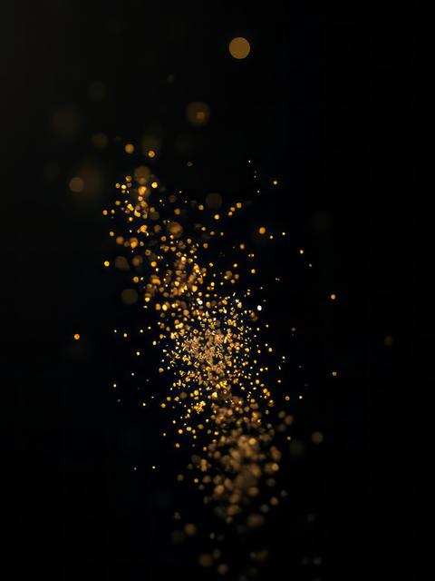 Gold dust suspended in mid-air catching light on a deep black background glitter dust particle Ultra