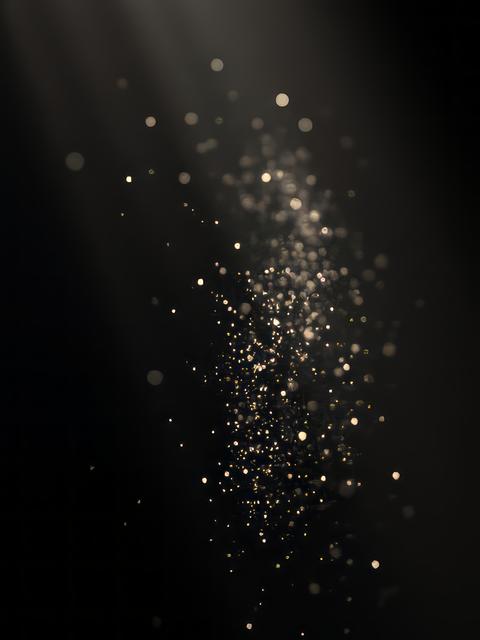 Organic dust particles floating in light ray on black background glittering sparkling glowing