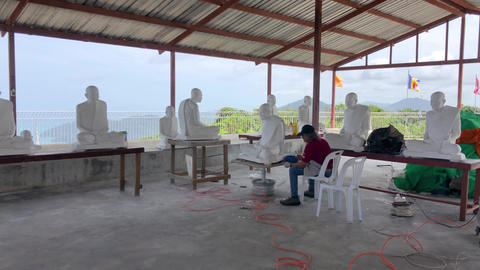 Phuket, Thailand - July 08 2022: Sculptor working on Buddha statues overlooking the sea in Thailand