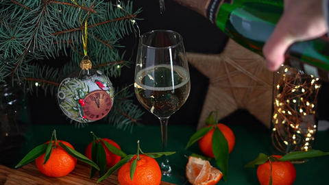 Pouring sparkling wine into wineglass on table with mandarins fir brunch and