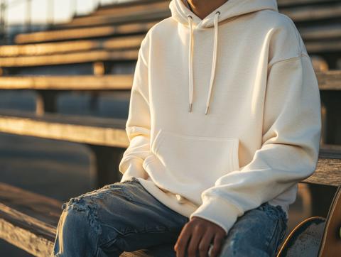 An Asian man sits on vintage stadium bleachers with an empty white hoodie. The