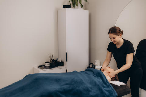 Young female masseuse in uniform doing back massage to woman in spa salon