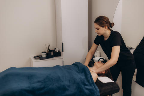 Young female masseuse giving shoulder and back massage to adult female client