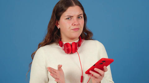 Confused Young Woman with Red Headphones Gesturing in Frustration